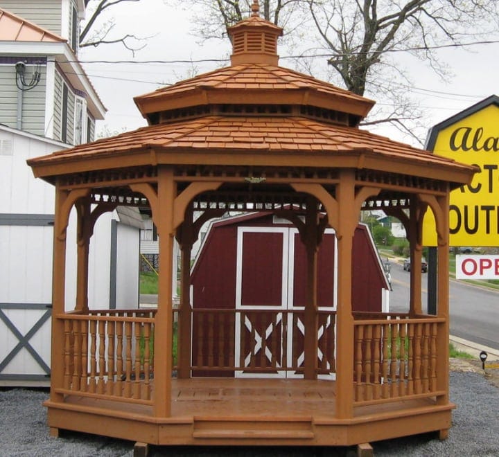 wood gazebo in front of a red barn