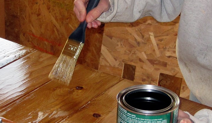 applying varnish to wooden bench