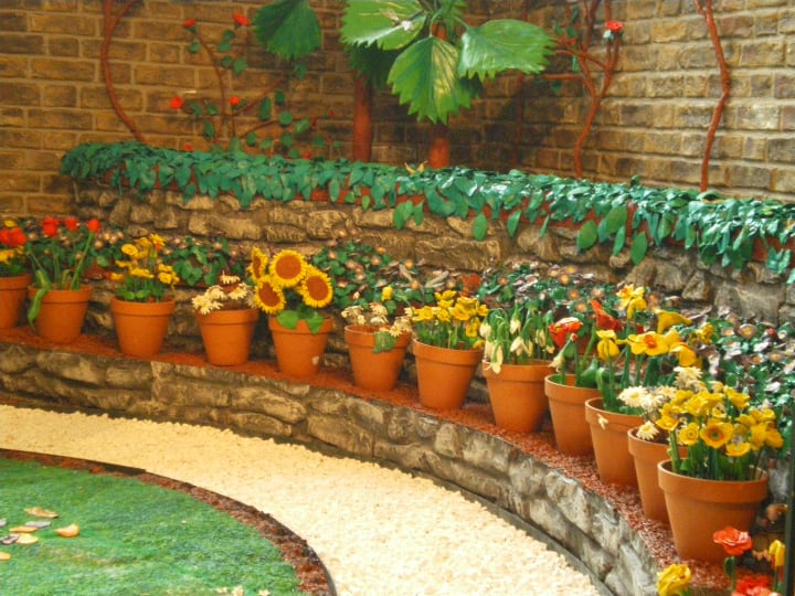 low maintenance potted landscaping in front lawn with artificial grass and rocks